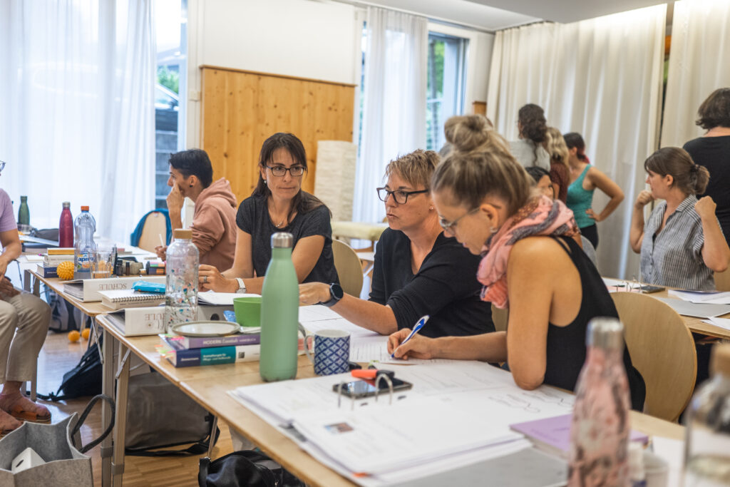 Teilnehmerinnen der Organsprache-Ausbildung beim Lernen mit Kursunterlagen und Austausch in der Community